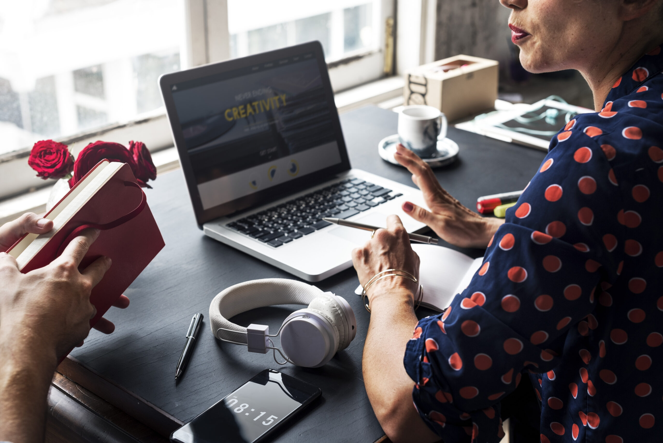 Woman Talking with Colleague and Using Laptop